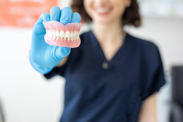 a dental professional holding a complete set of dentures