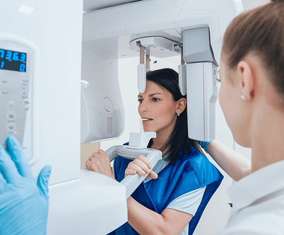 A patient is undergoing a dental X-ray procedure, assisted by a healthcare professional in a clinic setting.