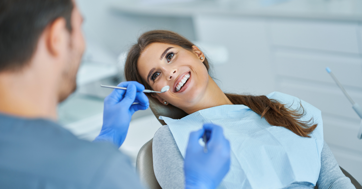 General Dentistry photo with woman in seat smiling while dentist is checking her mouth